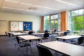 Un aula con mesas y sillas, una pizarra y una ventana con cortinas.