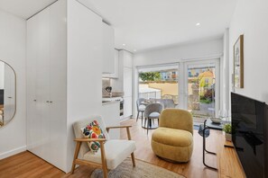 A modern living room with a sofa, armchair, and a TV. - Porto Garden Patio Retreat (Porto)