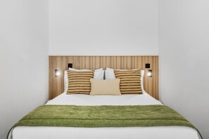 A bed with a wooden headboard, two wall-mounted lights, and a green throw blanket. - Porto Garden Patio Retreat (Porto)