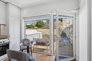 A modern kitchen with a built-in oven and a dining area with a table and chairs. - Porto Garden Patio Retreat (Porto)