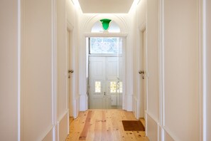 A hallway with white walls, a wooden floor, and a door with glass panels. - Porto Garden Patio Retreat (Porto)