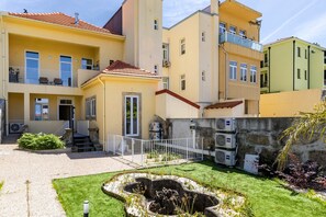 A multi-story hotel with balconies, a courtyard with a water feature, and air conditioning units. - Porto Garden Patio Retreat (Porto)