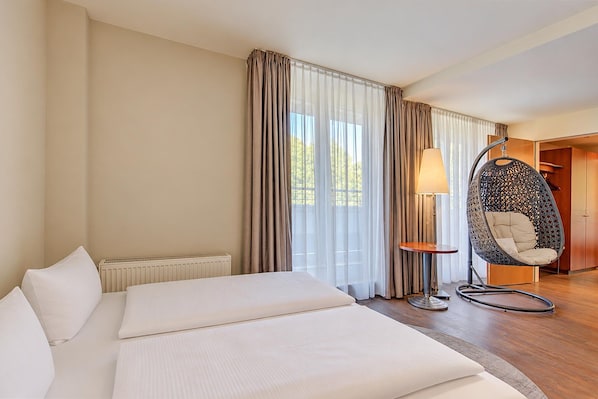 Une chambre d’hôtel avec un lit, un fauteuil suspendu, une lampe et une vue sur l’extérieur.