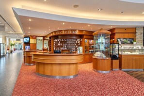 A reception area with a curved wooden desk, a bookshelf, and a display case.
