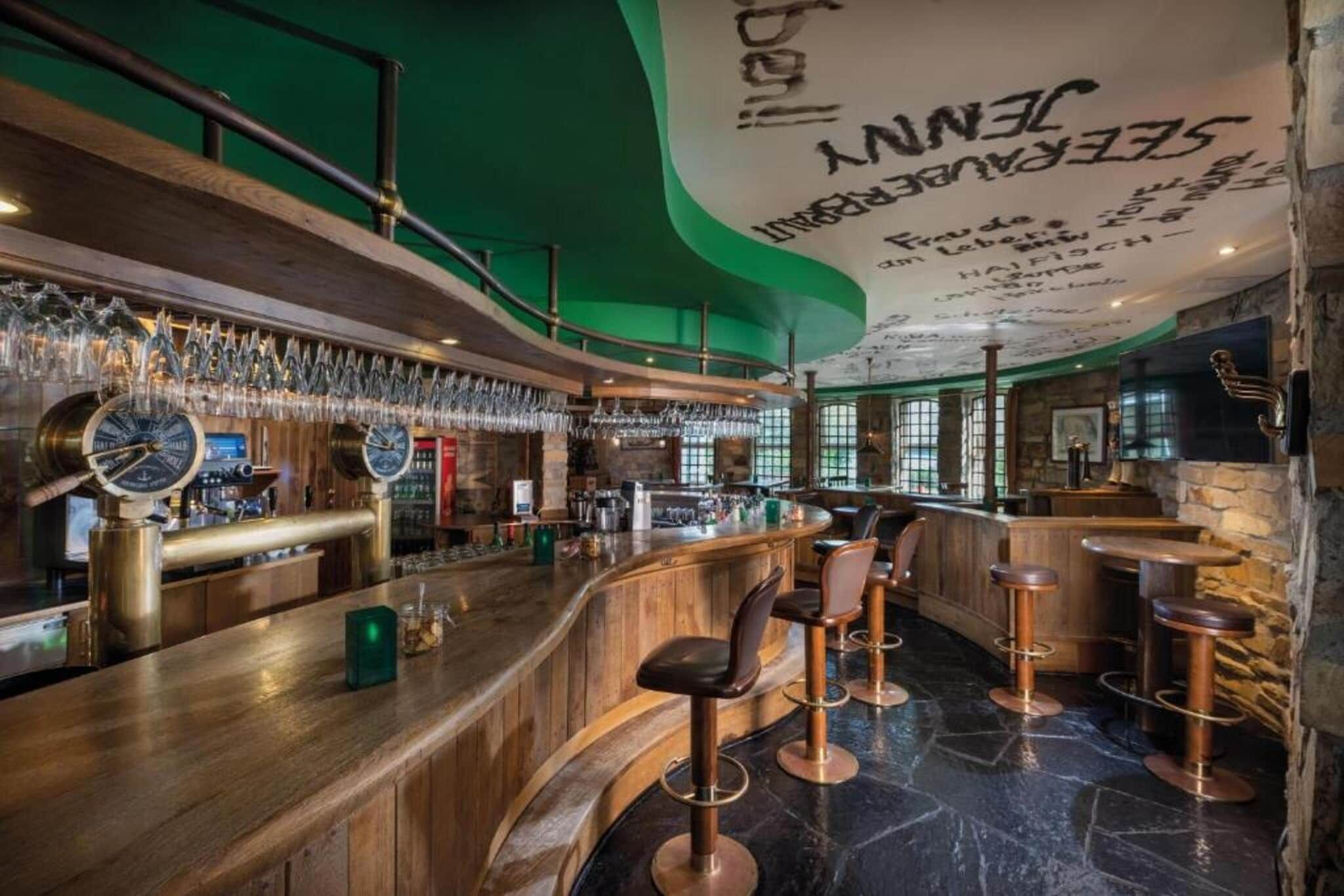 Un espace bar avec un comptoir en bois, des tabourets de bar et une horloge.