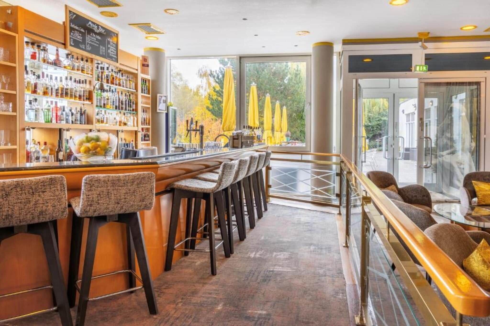 Un espace bar doté d’un long comptoir, de nombreux tabourets et offrant une vue sur l’extérieur grâce à de grandes fenêtres.