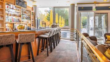 Un espace bar doté d’un long comptoir, de nombreux tabourets et offrant une vue sur l’extérieur grâce à de grandes fenêtres.