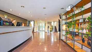 Ein Hotel-Empfangsbereich mit Empfangstresen und einer Treppe zu den oberen Stockwerken.