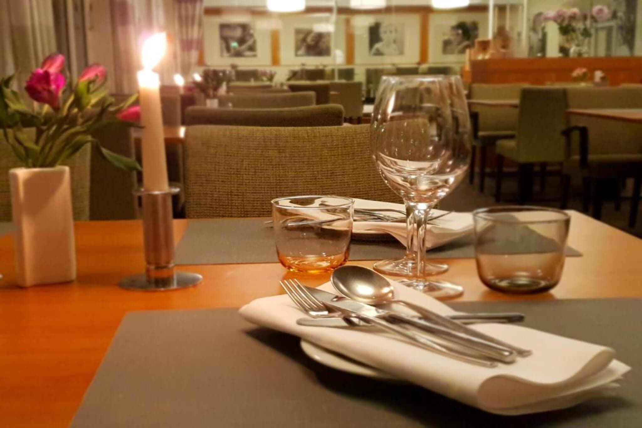 Une table à manger dressée avec une bougie, des verres à vin et des couverts, ce qui indique qu’un repas a été préparé.