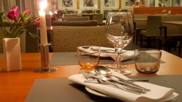 Une table à manger dressée avec une bougie, des verres à vin et des couverts, ce qui indique qu’un repas a été préparé.