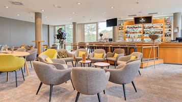 A modern lounge area with seating, a bar, and a view of the outdoors.