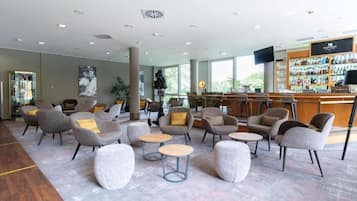 Un hall d’entrée spacieux avec plusieurs coins salon, un bar et de grandes fenêtres.