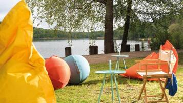 A lakeside picnic setup with a table, chairs, and colorful balls.