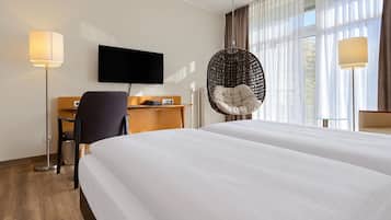 Een hotelkamer met een bed, een bureau, een stoel, een televisie en een hangstoel.