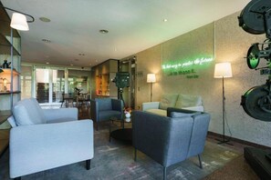 Un moderno vestíbulo de hotel con asientos, una mesa de centro y un letrero de neón en la pared.