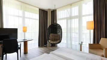 Habitació d'hotel amb un llit, dues cadires, un escriptori, una televisió i una cadira penjant.