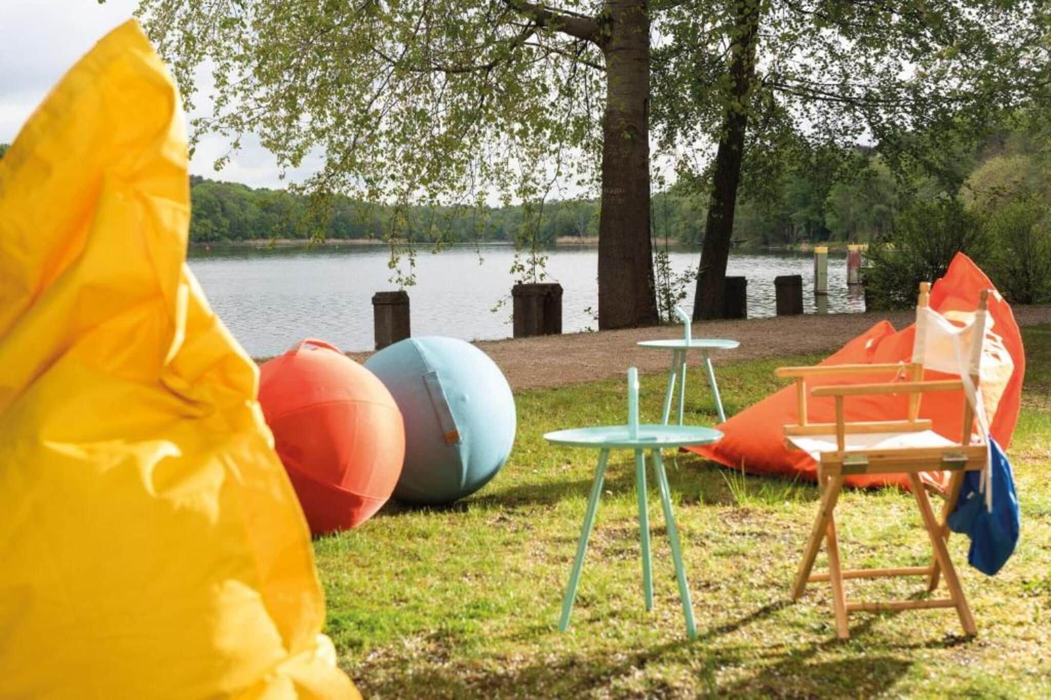 Ein Picknick am Seeufer mit Tisch, Stühlen und bunten Bällen.