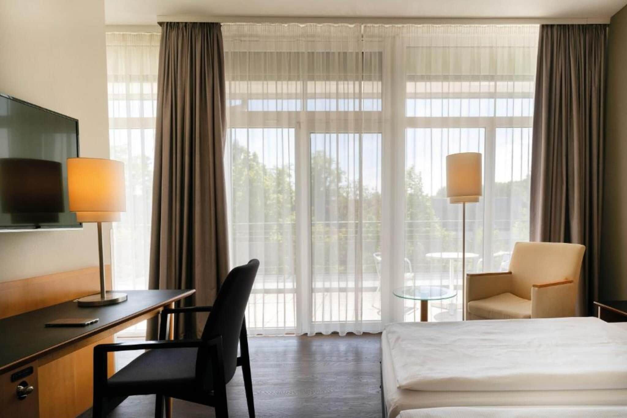 Une chambre d’hôtel avec un lit, un bureau, une chaise, une télévision et une lampe.
