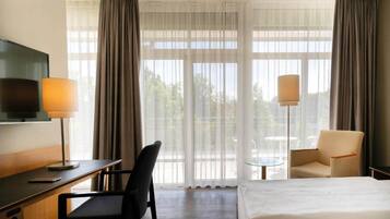 Une chambre d’hôtel avec un lit, un bureau, une chaise, une télévision et une lampe.