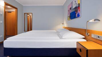 Ein Hotelzimmer mit einem Doppelbett, Nachttischlampen, einem Holznachttisch, einem Spiegel und einem farbenfrohen abstrakten Gemälde an der Wand.