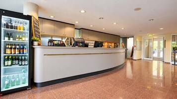 Eine Hotelhalle mit Rezeption, einer Getränkekühlbox und einem gefliesten Boden.