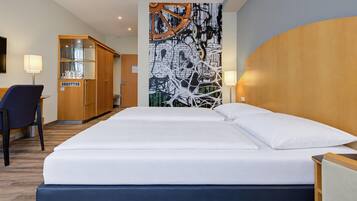 Ein Hotelzimmer mit einem Bett, einem Schreibtisch, einem Stuhl, einem Kleiderschrank und einer Wand mit einem Grafikdesign.