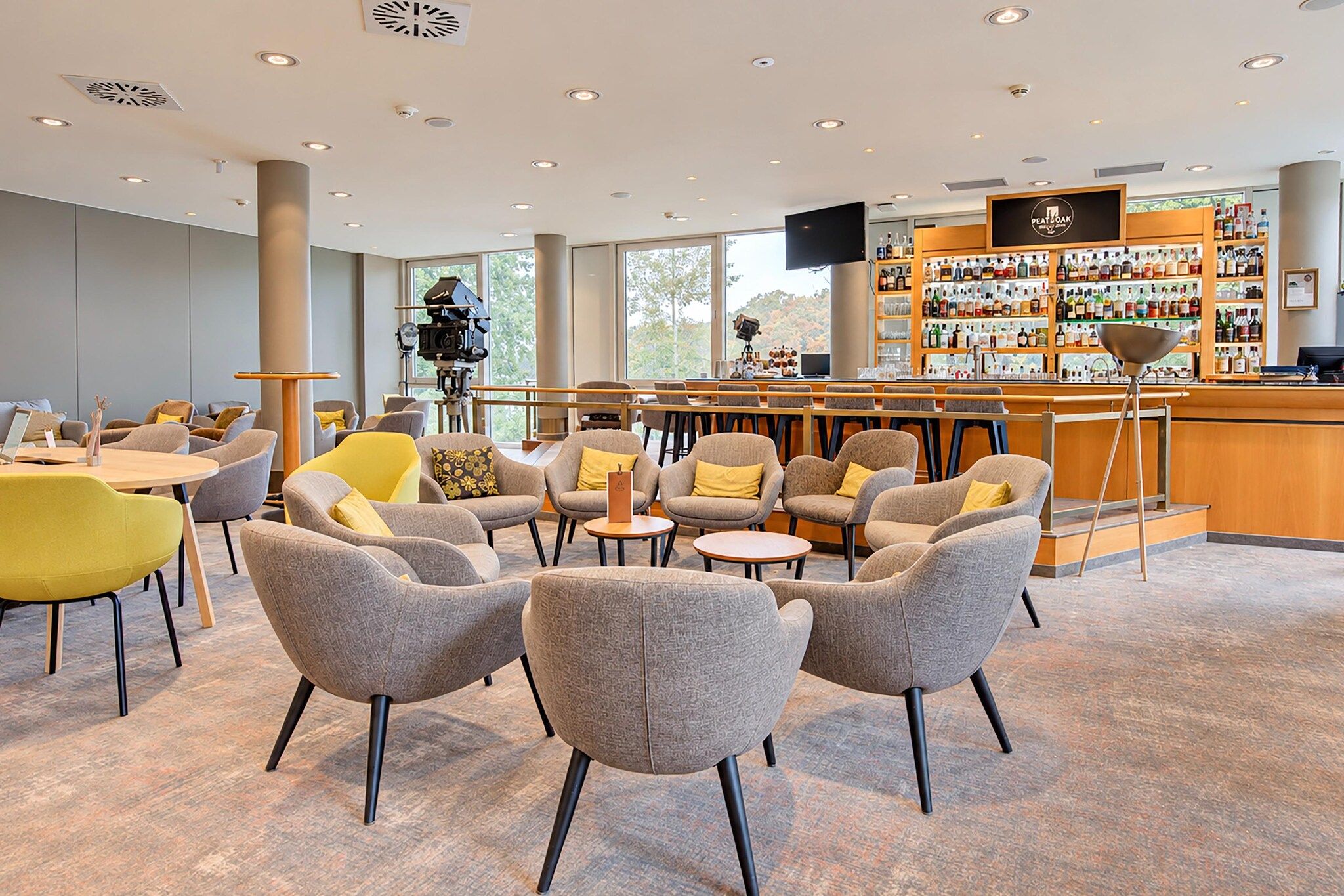 Ein moderner Lounge-Bereich mit Sitzgelegenheiten, einer Bar und Blick ins Freie.
