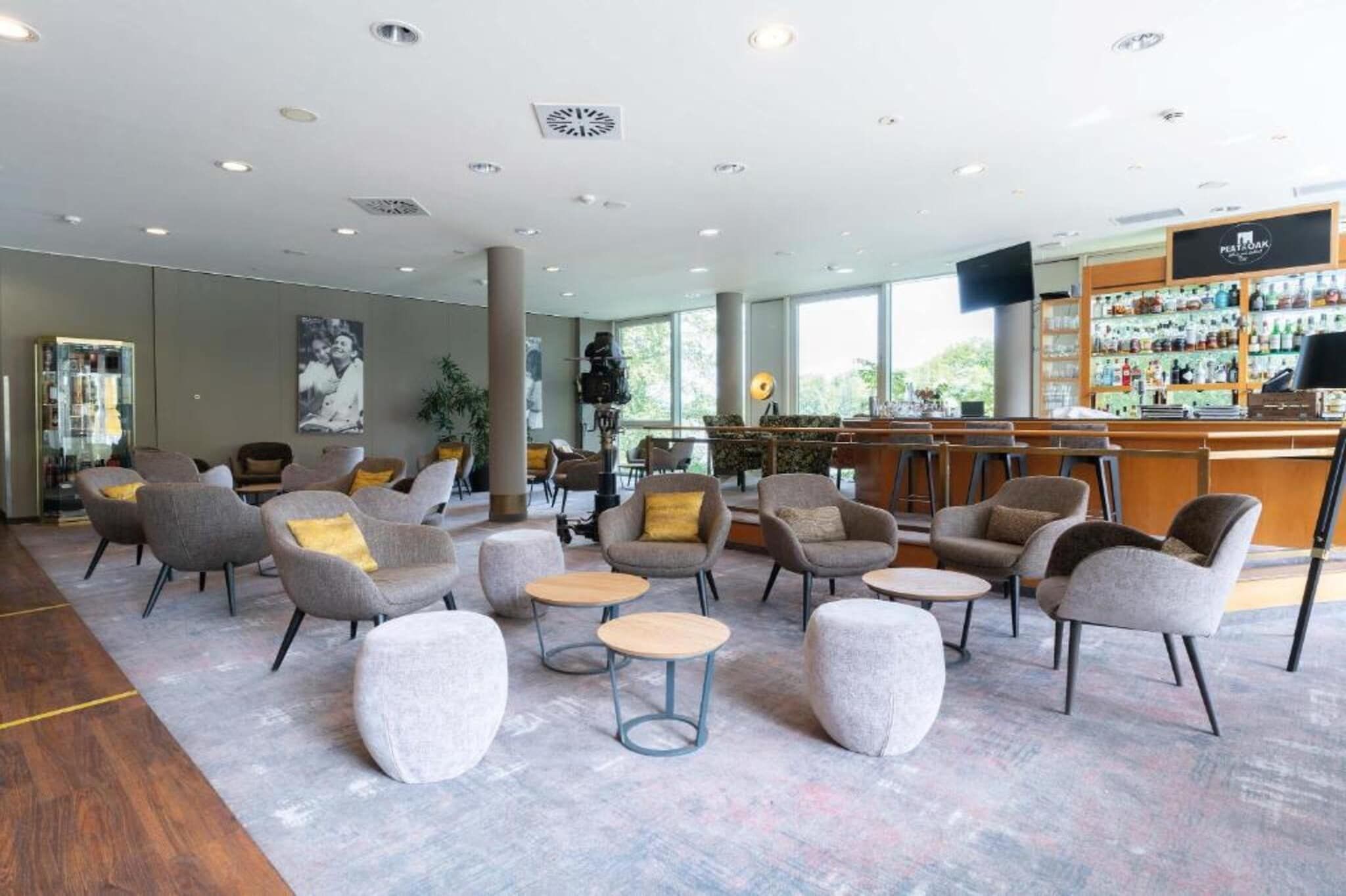 Un hall d’entrée spacieux avec plusieurs coins salon, un bar et de grandes fenêtres.