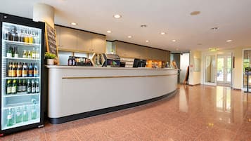 Un hall d’hôtel comprenant un comptoir d’accueil, un réfrigérateur pour les boissons et un sol carrelé.
