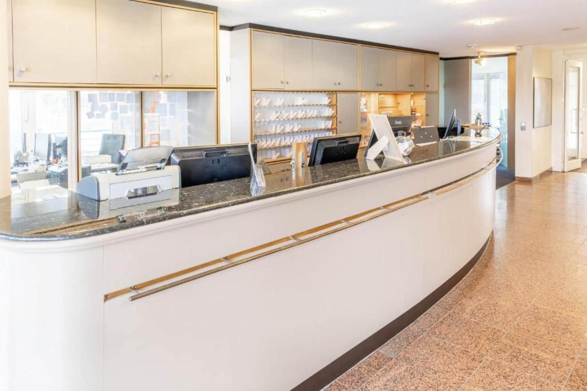 Un espace d’accueil moderne, doté d’un comptoir incurvé, de vitrines et offrant une vue sur le paysage urbain grâce à de grandes fenêtres.