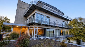 Un hôtel moderne doté d’une façade en verre, d’un espace extérieur aménagé et d’une enseigne indiquant « Avendi Hotel Potsdam ».