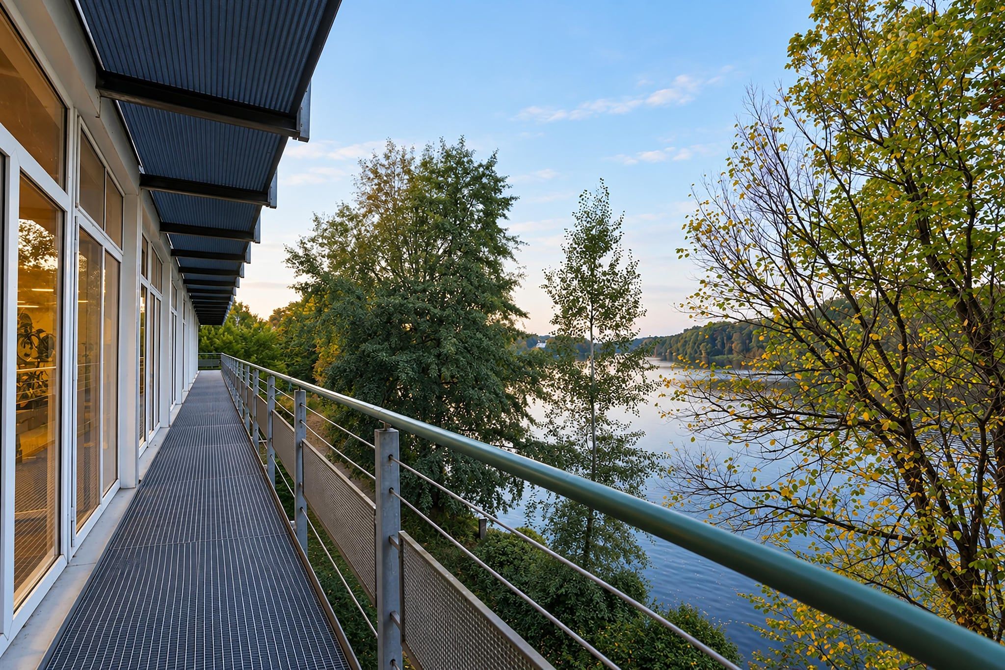 Een modern gebouw met een overdekte gang en uitzicht op een waterpartij.