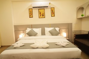 A hotel room with a large bed, two bedside lamps, a headboard, and three wall-mounted artworks. - Hotel Elite Suites (Gurugram)