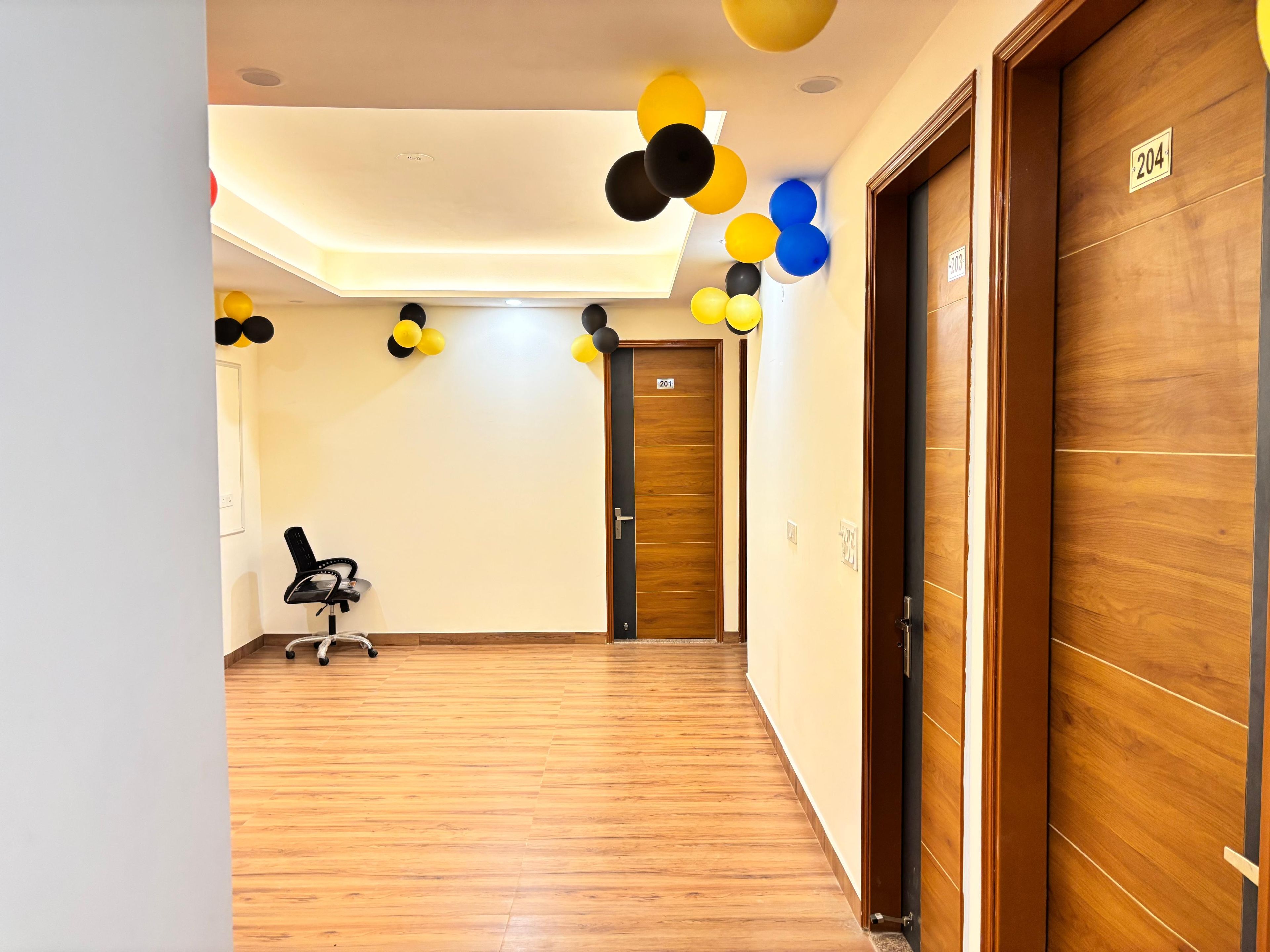 A hotel corridor with wooden flooring, a desk with a chair, and doors numbered 201 and 204.