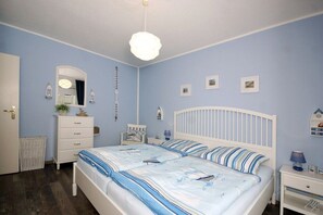 A bedroom with two beds, a dresser, a nightstand, and a hanging light fixture. - Holiday apartment with 1 bedroom (Seebad Heringsdorf)