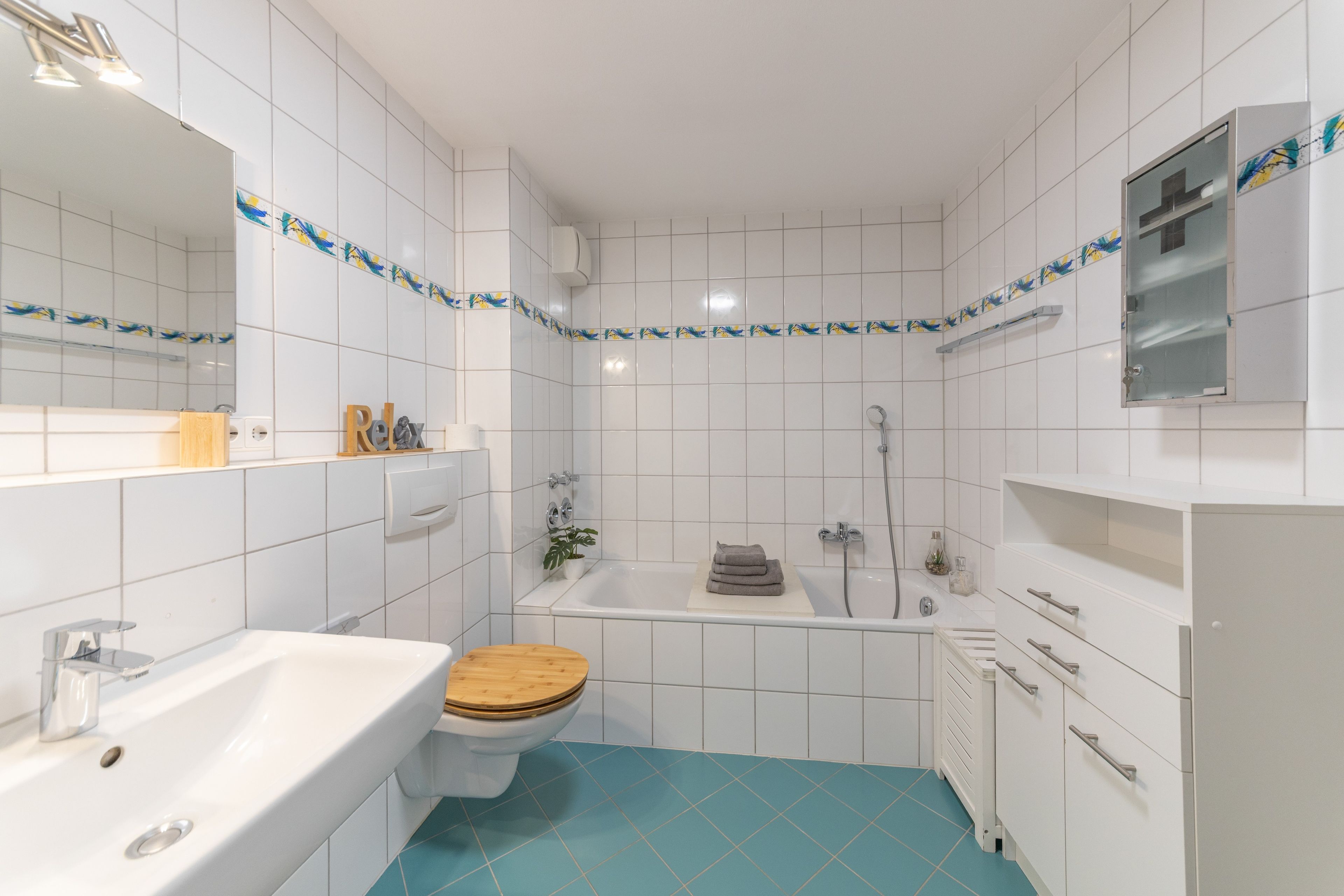 Ein Badezimmer mit einem weißen Waschbecken, einer Toilette mit Holzsitze, einer Badewanne und einer Dusche.