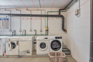 Un cuarto de lavandería con dos lavadoras, un secador y varias tuberías y mangueras.
