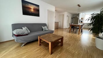 A modern living room with a grey sofa, a wooden coffee table, and a large potted plant.