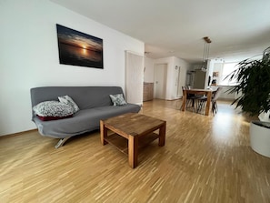 A modern living room with a grey sofa, a wooden coffee table, and a large potted plant.