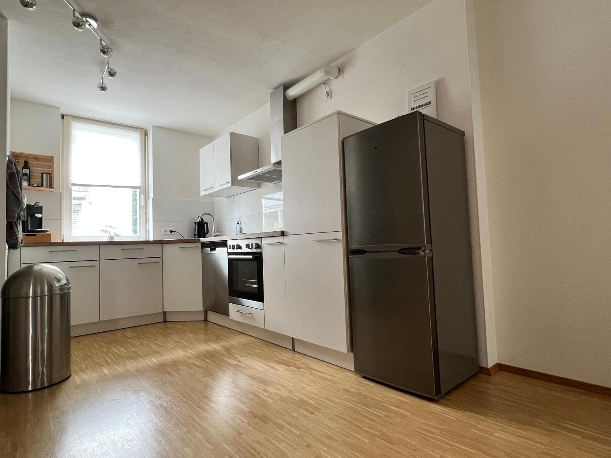 Una cocina moderna con armarios blancos, un refrigerador de acero inoxidable y un horno empotrado.