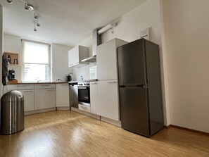 Una cocina moderna con armarios blancos, un refrigerador de acero inoxidable y un horno empotrado.