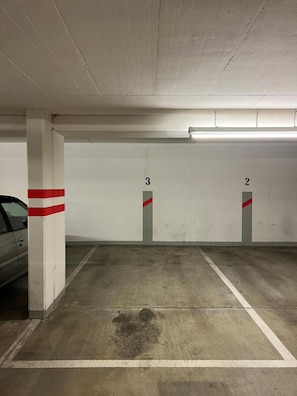 A parking garage with concrete floors, white walls, and numbered parking spaces.
