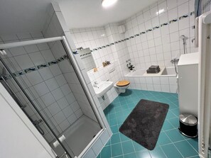 Un baño con ducha, inodoro, lavamanos y bañera.