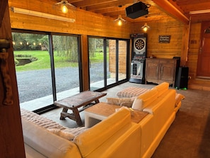 A cozy room with a wooden interior, a dartboard, and a seating area with a table and cushions.
