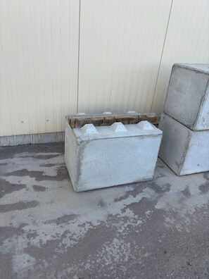 A concrete structure with a rough texture, positioned against a vertical wall.
