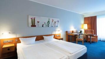 Une chambre d’hôtel avec un lit double, un bureau avec une chaise, une lampe et un tableau au mur.