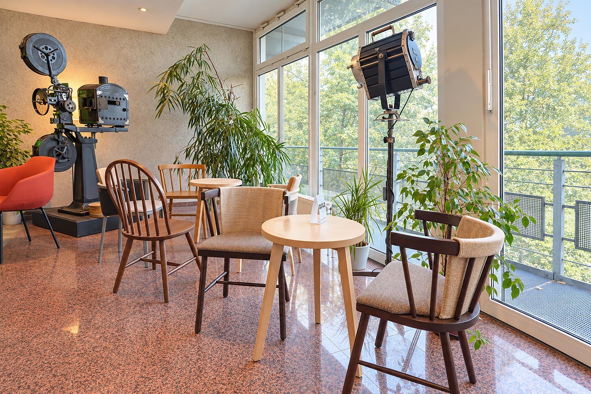 Ein modernes Interieur mit einer Sitzecke, großen Fenstern und einer Mischung aus Möbeln, darunter Stühle und Tische.