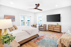 A bedroom with a bed, a dresser, a television, and a view of the outdoors. - Laguna Matata by Kaiser | Waterfront Little Lagoon | Heated Pool | Near Beach (Gulf Shores)