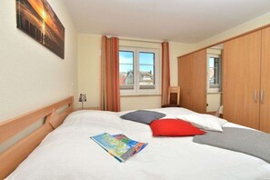 Ein Hotelzimmer mit Bett, Fenster, Kleiderschrank und einem Bild an der Wand.