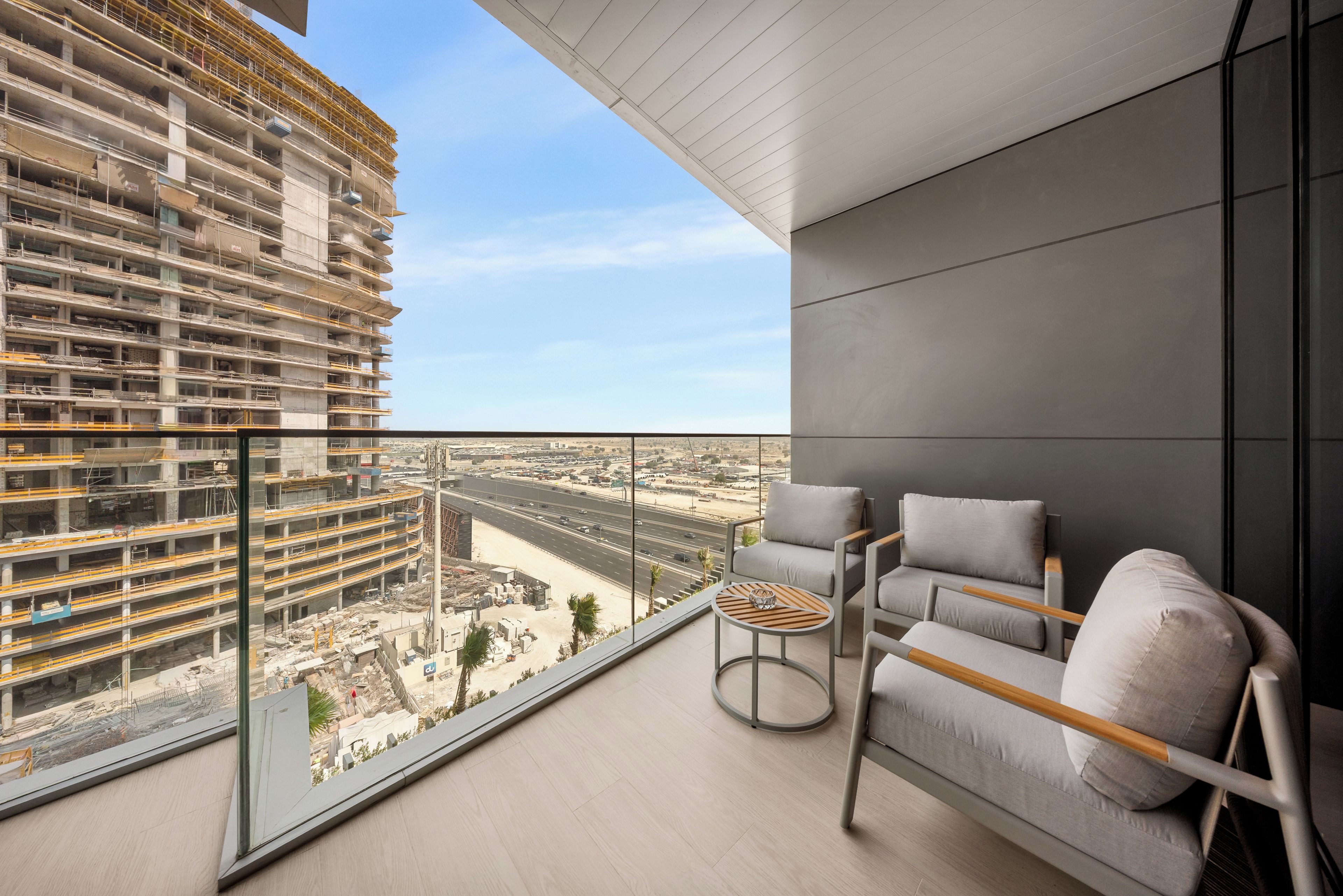 A balcony with a view of a construction site and a modern building.